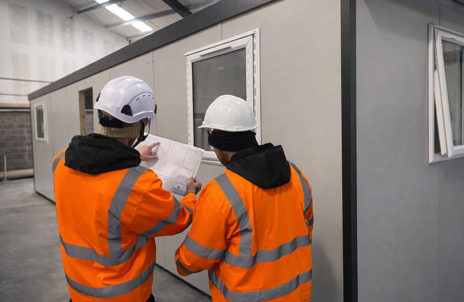 Spacemaker team checking a drawing beside a modular building